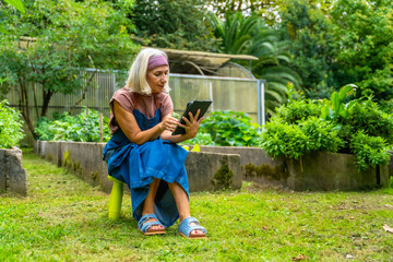 Senior woman using tablet in garden, combining technology with gardening