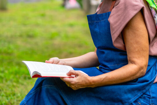 Senior woman relaxing, reading book in green park