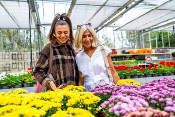 Mother and daughter shopping for flowers in greenhouse