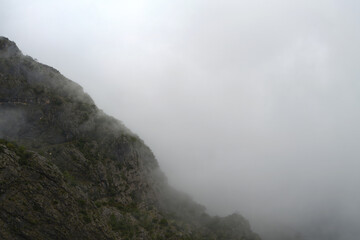 Dense fog shrouding mountains by lakeside
