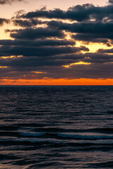 Bright fiery sunrise over the Black Sea in Obzor, Bulgaria with dramatic clouds and dark rippling waves creating bold coastal contrast