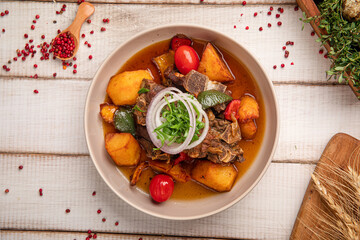 Traditional Central Asian dish with fried meat, golden potatoes, cherry tomatoes and fresh onions in a bowl