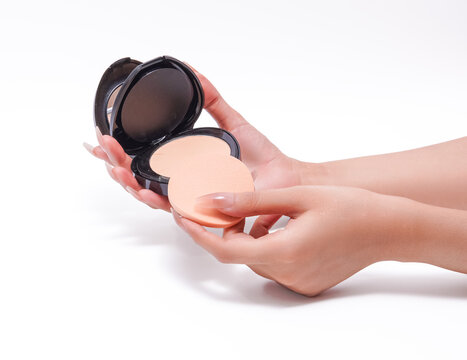 Woman hands holding compact face powder and makeup sponge.