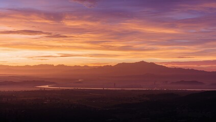Obraz premium A scenic sunrise illuminating the silhouette of mountains in the background, seasonal change