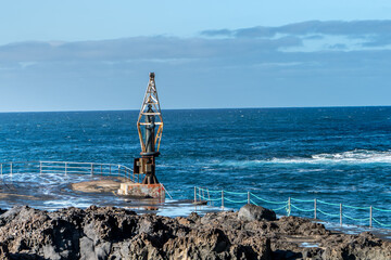 Rocky coastline with small boat crane in El Pris, Tenerife