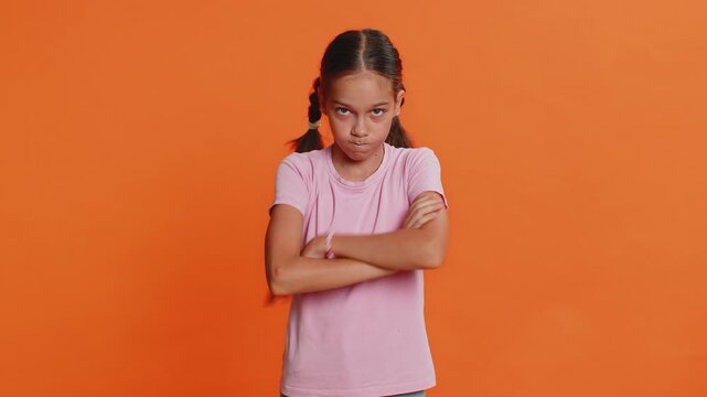 Dissatisfied young preteen child girl kid expressing disbelief irritation, feeling bored nervous, disappointed in result, bad news, fail, lose game. Teenager children isolated on orange background