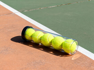 Tennis balls tube on boundary between green and orange court