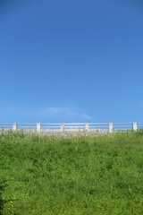 快晴の青空と緑の草が生い茂る堤体の歩道の風景16