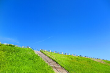 快晴の青空と緑の草が生い茂る堤体の歩道の風景15