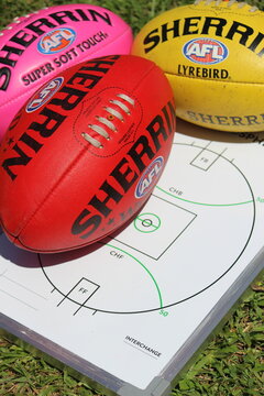 A red, yellow and pink AFL football on a coach's tactical board