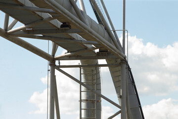 Detailed view of an industrial conveyor system featuring a robust structural framework under a clear sky, highlighting engineering and design for efficient transport.