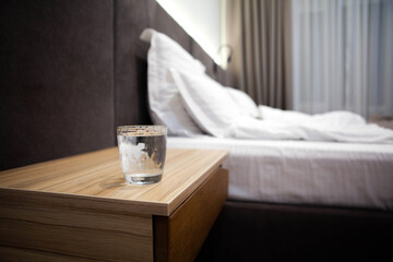 Glass of water on a bedside table in a cozy bedroom, symbolizing hydration, wellness, and post-workout recovery in a calm self-care setting.