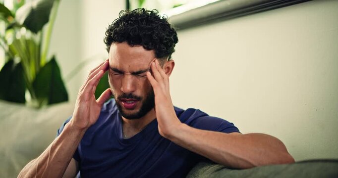 Headache, massage and man on couch with tension, dehydration or vertigo in stress management. Pain, brain fog and male person in house with migraine, exhausted and temple ache in living room.