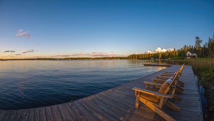 Obraz premium Row of Adirondack chairs on a wooden dock at sunset, ideal for relaxation
