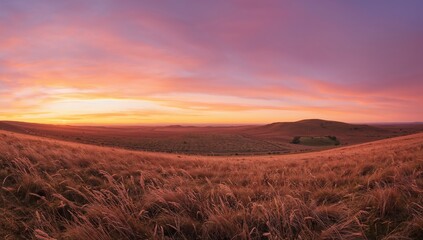Vibrant panoramic view of a golden sunset illuminating a field and rolling hills in warm pastel shades, seasonal change