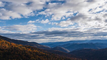 Fototapeta premium The interplay of cumulus and stratus clouds over mountains, showcasing seasonal change