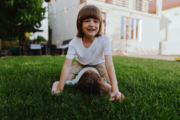 Fototapeta premium Happy children playing on green grass, enjoying their time outdoors in a sunny garden. Their laughter and joy create a lively atmosphere of childhood innocence.