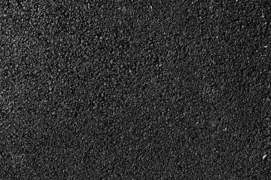 close-up texture of smooth, freshly laid asphalt surface showcasing fine granules and a uniform appearance, neutral background, clear negative space, clean composition, balanced framing, minimalist