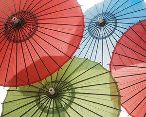 Vibrant Asian umbrellas in red, green, and blue create a stunning colorful display, perfect for travel blogs or festive event promotions, adding a touch of culture