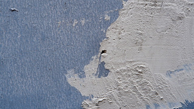 Weathered wall with peeling plaster and rough texture, showing decay and aging surface details.