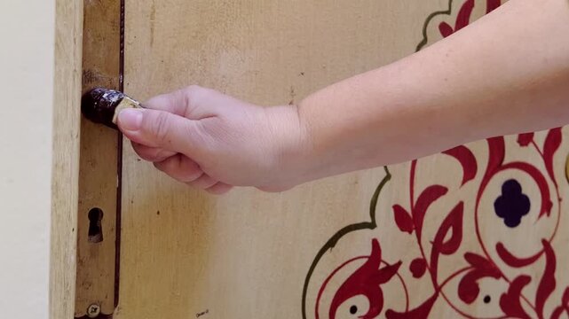 Closing vintage Moroccan door with carved wood, female hands in motion, mystery, elegance, riad interior, private space