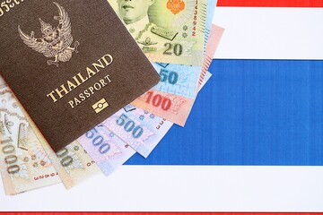Thai baht currency money bills and passport lies on flag close up. The concept of travel and vacation