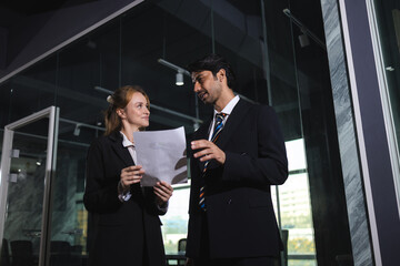 Result Smiling professional business people in dark suit reviewing document in modern office interior, showing collaboration and positive discussion