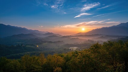 Obraz premium The sun ascends amidst mist and mountains in the early hours, morning haze