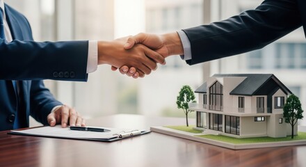 Successful real estate deal signing with handshake and model house on the table in a modern office setting
