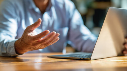 Obraz premium Man working on a laptop in warm natural light, captured in a thoughtful, quiet moment. Perfect for productivity, tech use, remote work, and digital life visuals.