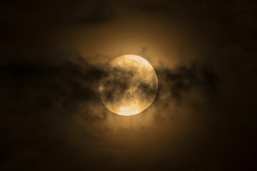 Pełnia księżyca za ciemnymi chmurami nocnego nieba, tajemnicza złota poświata. © Henryk Guziak