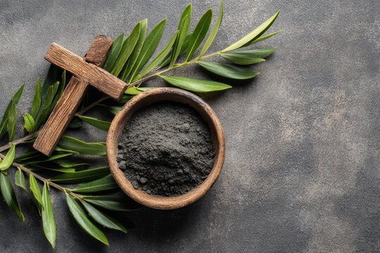 Above view of bowl with burnt ashes, wooden Christian cross and olives on gray concrete background, Ash Wednesday concept