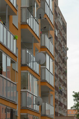 A view of modern apartment buildings featuring balconies and satellite dishes in an urban setting. Ideal for real estate and architectural designs.