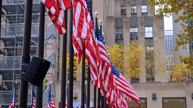 Row of American flags in the street of New York, USA. A building with construction scaffolding at backdrop.