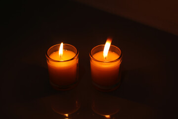 A candle burned on a glass holder in the dark, a symbol of hope.