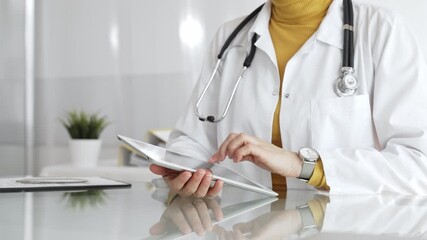 Doctor using tablet, working in clinic office, health care professional analyzing electronic medical records data. Medicine, healthcare and science concept