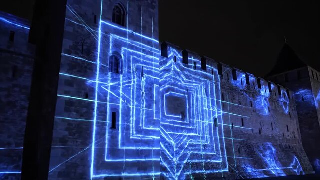 The illuminated medieval Carcassonne city walls with blue laser patterns including concentric squares and gridlines at night