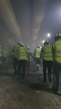 Construction workers walking out from a dark smoke filled tunnel