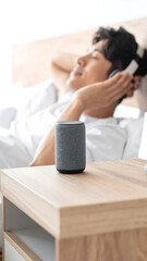 Relaxing at Home with Music A Man Enjoys Audio Through a Smart Speaker in His Bedroom