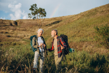 Senior couple rests among wild grassy hills at sunset