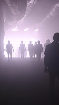 silhouette of many construction workers walking out from a large tunnel