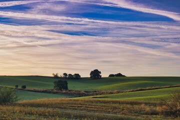 Fototapeta premium Beautiful landscape with rolling hills and clouds during sunset in a serene countryside setting