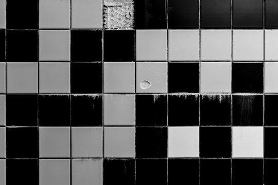Monochrome Kachelwand mit besch&auml;digten Fliesen und grafischem Muster &ndash; urbane Textur, Kontraste und minimalistische Architekturdetails