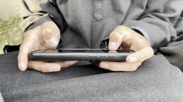 Closeup shot of a young boy playing online games on his smart phone. Boy playing online game on his smart phone which have negative impact on the mental health of young people 