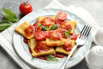 Delicious ravioli with tomato sauce and basil served on grey table, closeup