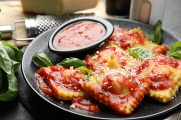 Delicious ravioli with tomato sauce, cheese, grater and basil on grey table, closeup