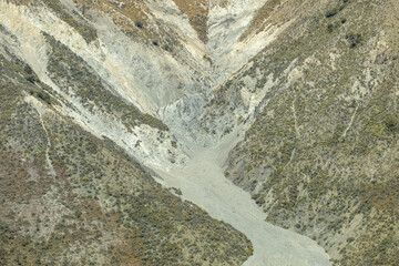 Aerial view of a dry mountain valley with rugged slopes and sparse vegetation.