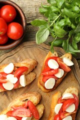 Tasty bruschettas with mozzarella cheese, tomatoes and basil on wooden table, flat lay