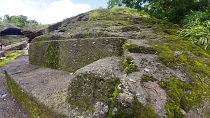 Ancient moss-covered rock-cut stairs leading to Buddhist caves at Kanheri, featuring a small weathered carving on the corner.