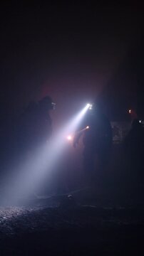 Rescue forces search for survivors inside a dark tunnel using flashlights